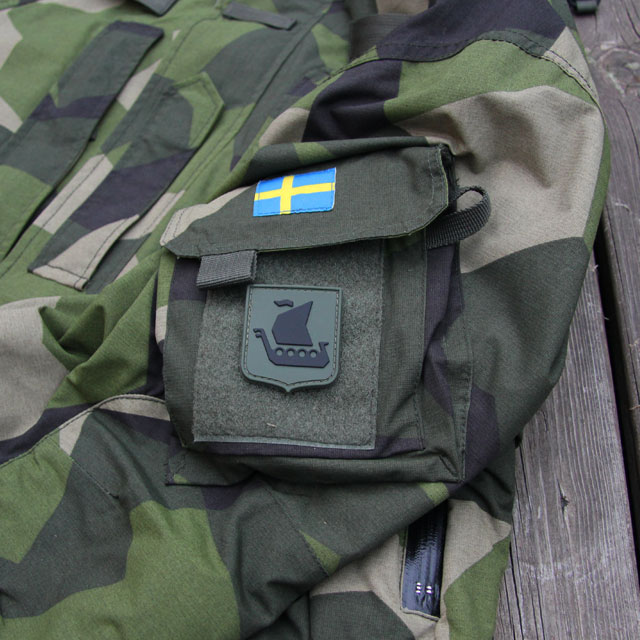 En Svensk flagga och ett Vikingship Shield Hook PVC Green/Black Patch märke på en NCWR Jacket M90.