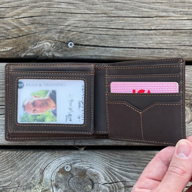 En Plånbok Mörkbrun Läder från TAC-UP GEAR visar ett av de genomskinliga plastfacken för kort
