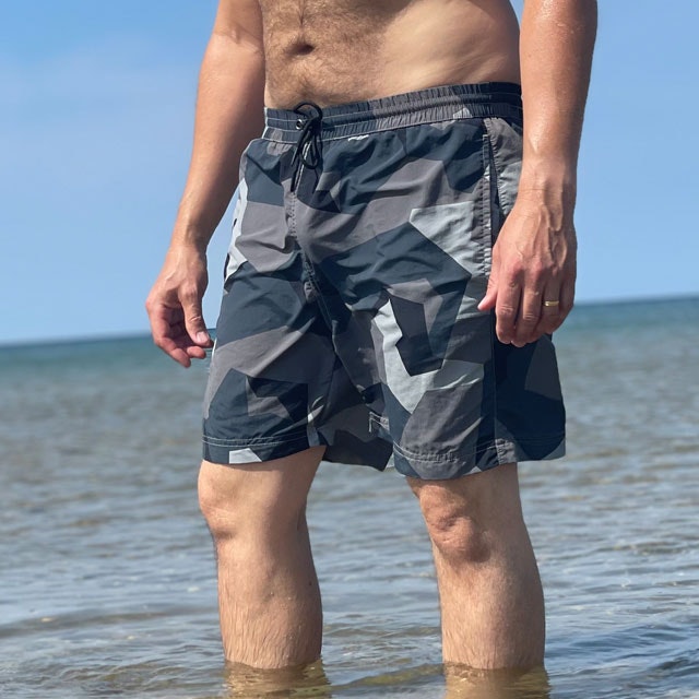 POSEIDON Swim Shorts M90 Grey seen from the front on model in the sun with ocean as background