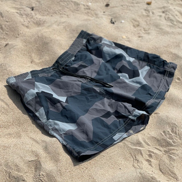 POSEIDON Swim Shorts M90 Grey lying flat on the beach seen at an angle