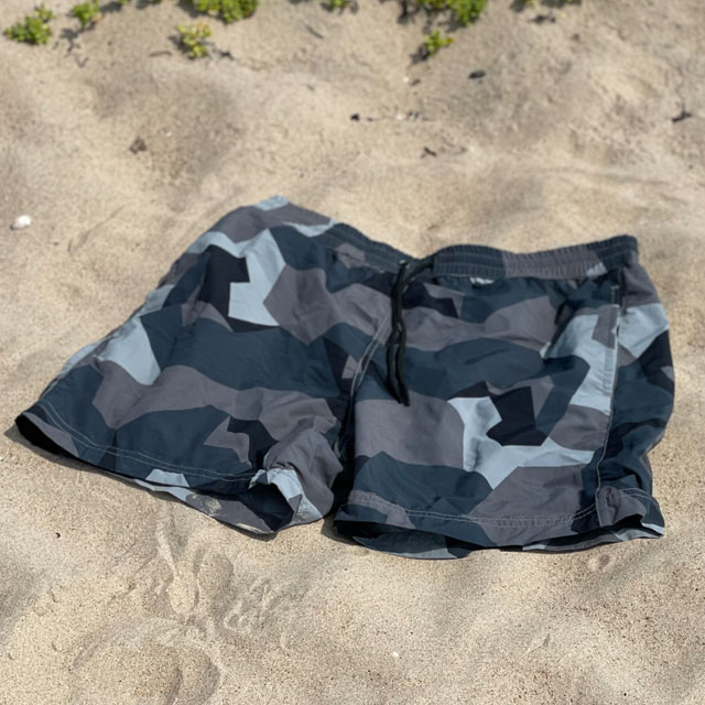 A closer look at a pair of POSEIDON Swim Shorts M90 Grey lying flat on the beach
