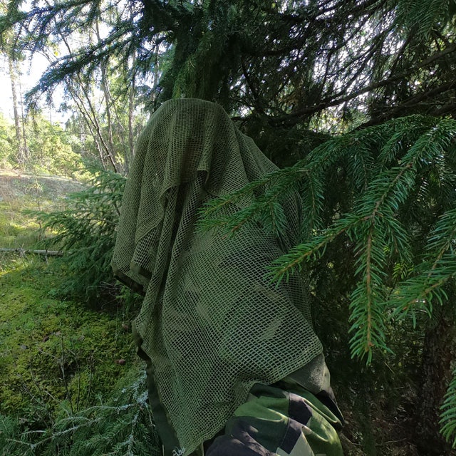 Showing the excellence in camouflage wearing a draped Scrim Net Scarf Green draped and in the Swedish forest