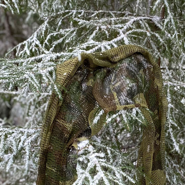 a Scrim Net Scarf Woodland on branches of a tree with snow on
