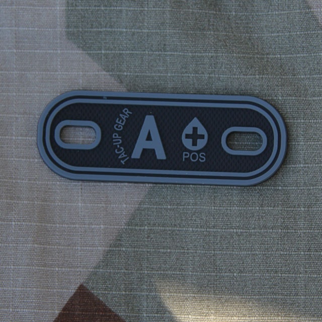 A+ Bloodtype Tag Black PVC with M90 camouflage background.