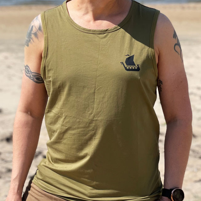 A male model wearing Tank Top Khaki Green from TAC-UP GEAR on a Swedish beach and seen from the front