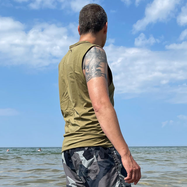 Tank Top Khaki Green from TAC-UP GEAR on model with tatoo´s at the ocean seen from a side angle