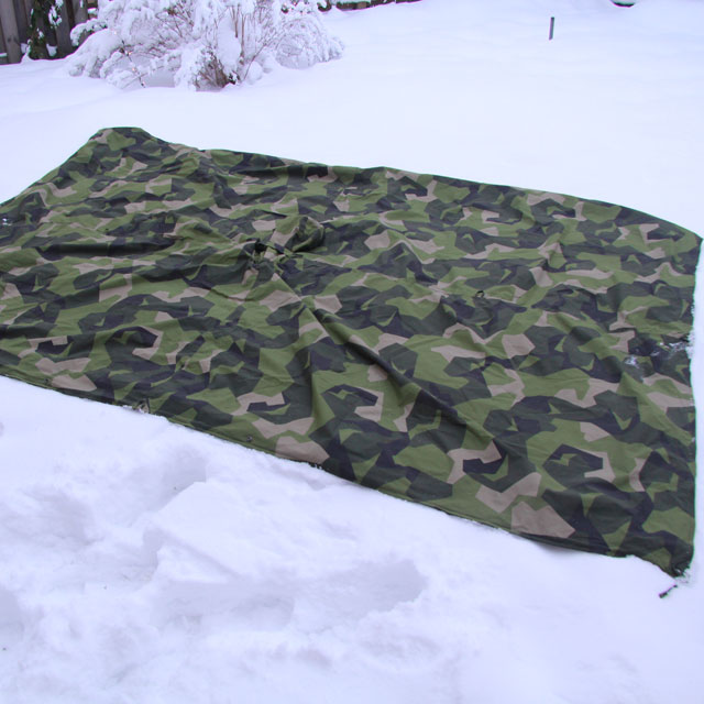 Rectangle Tarp Poncho M90 spread out outdoors on wintery ground.