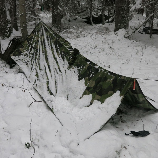 Snowdrift caked on the side of a Tarp Poncho M90 used as basha for the nigh in Swedish winter.