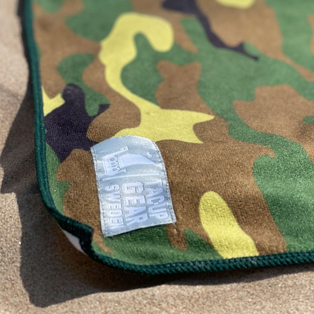 A close up on a Towel Camouflage from TAC-UP GEAR laying in the sun on the beach