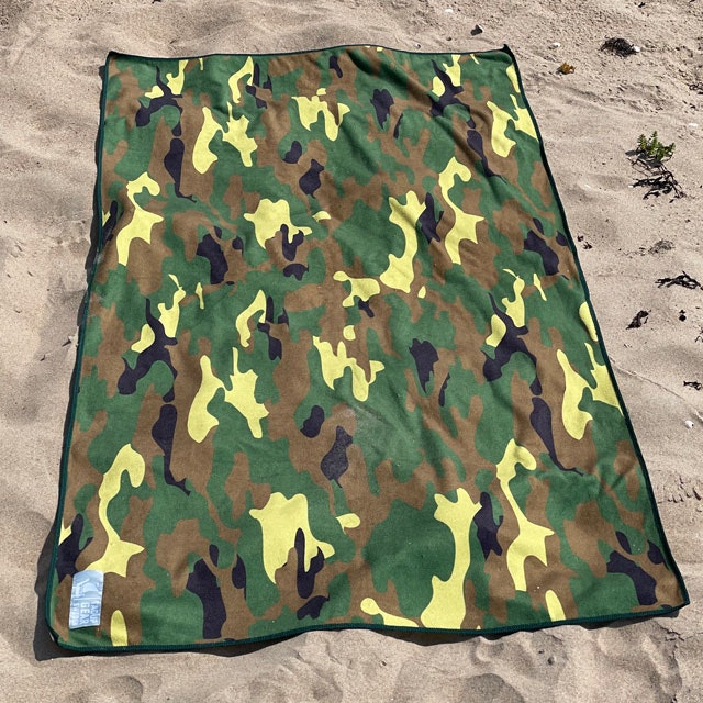 A Towel Camouflage from TAC-UP GEAR lying flat on beach sand