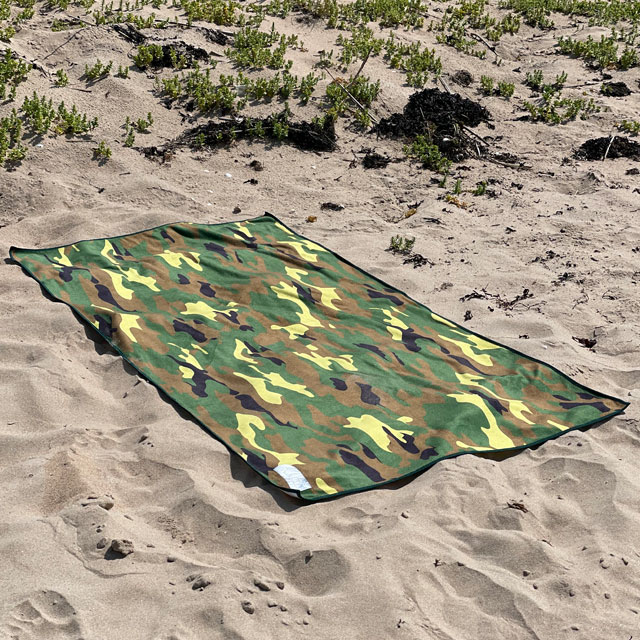 The Towel Camouflage from TAC-UP GEAR lying flat on beach sand and seen from an angle