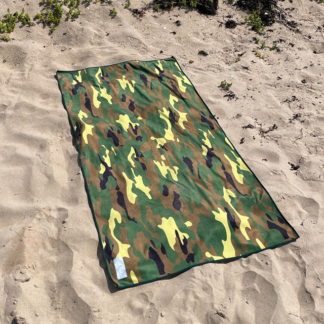 The Towel Camouflage from TAC-UP GEAR lying flat on beach sand