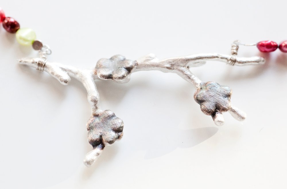 Silverkvist med oxiderade blommor på pärlhalsband
