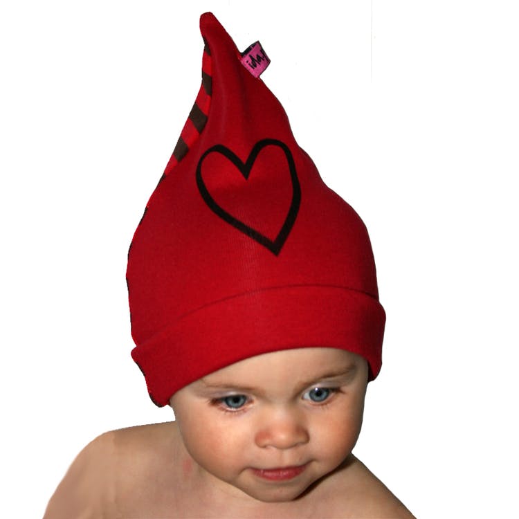 Ett barn med en röd mössa med ett handtryckt hjärta på.