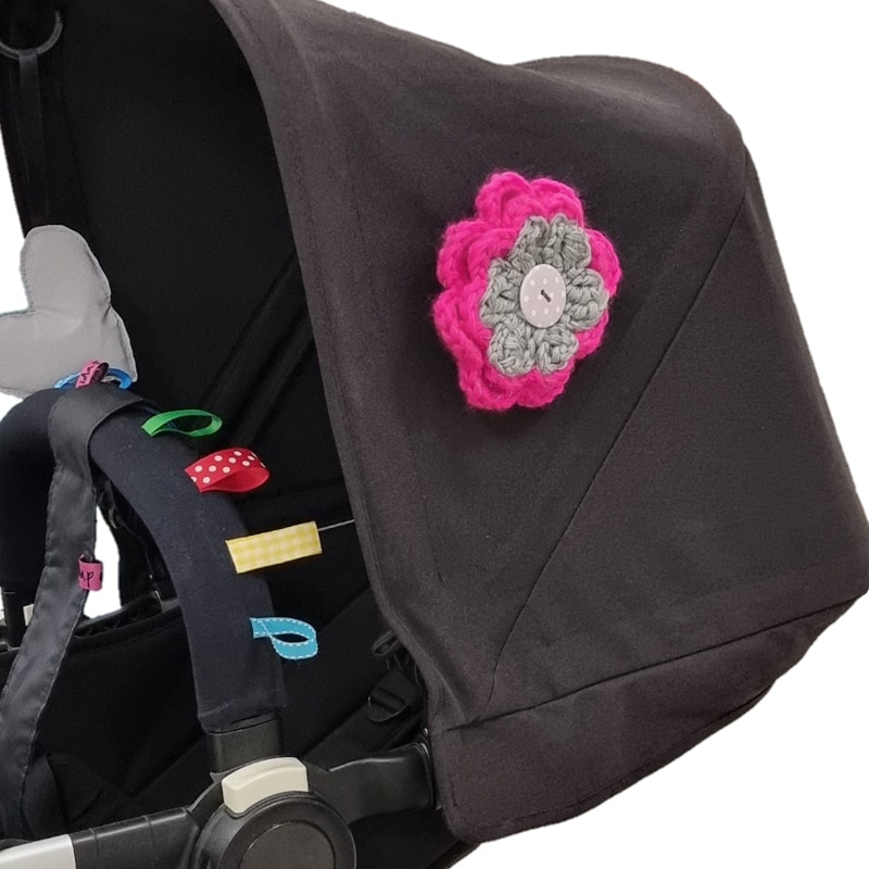 Barnvagnsreflex virkad av reflexgarn i rosa och grått som en blomma