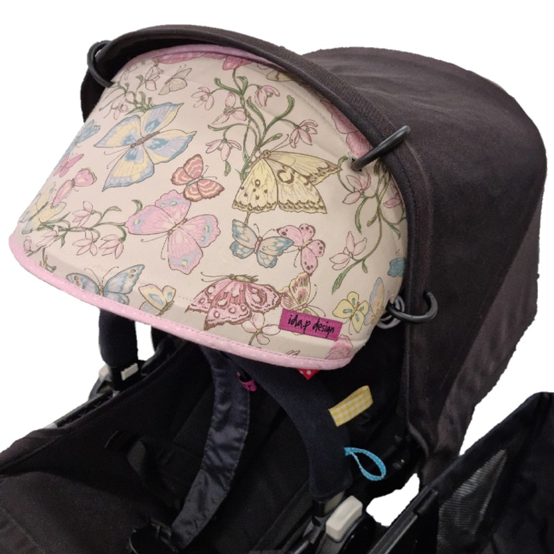 Solskydd barnvagn benvitt med fjärilar i rosa, blå, gult och grönt.