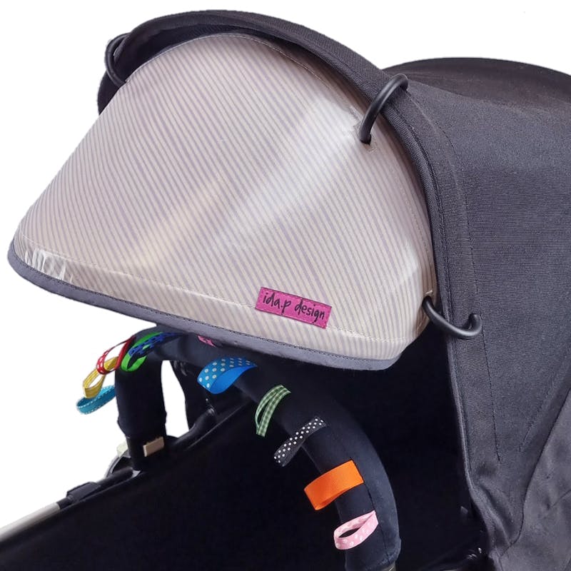 Solskärm att fästa på suffletten på barnvagn. Sydd i lila och vit-randig vaxduk.