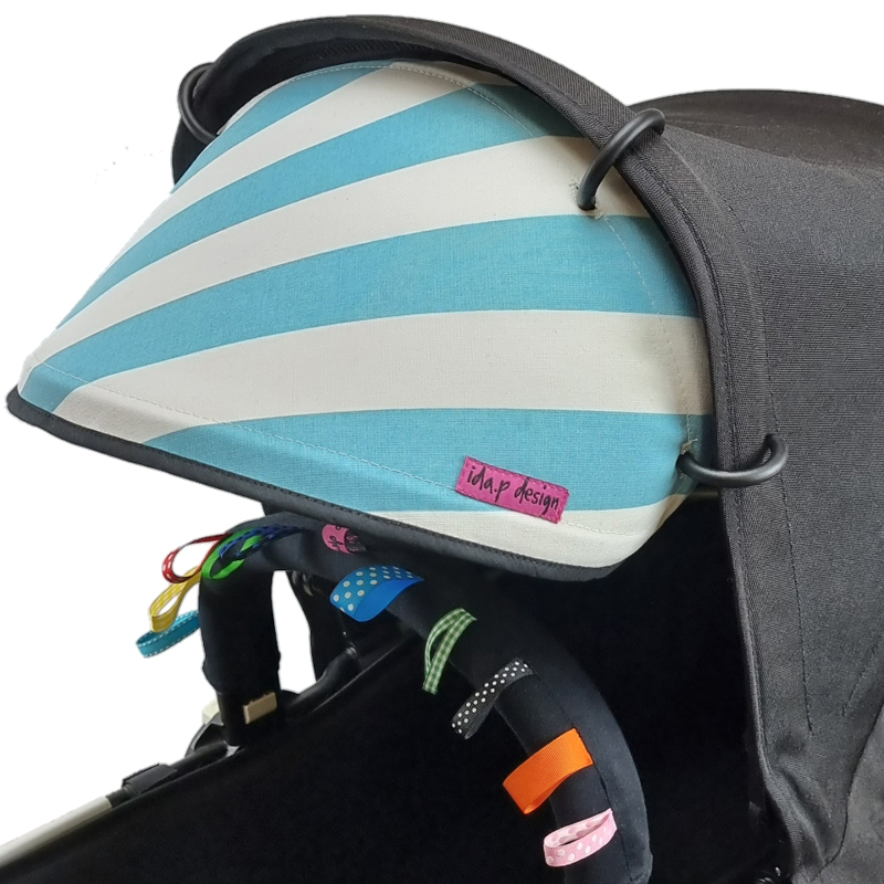 Solskydd till barnvagn i turkos och vit-randigt tyg. Svart kantband