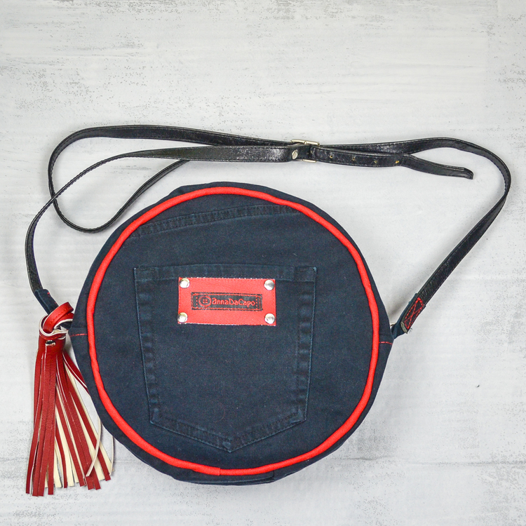 Svart rund väska med jeansficka företagsmärkt AnnaDacap i rött. Svart lång läderrem