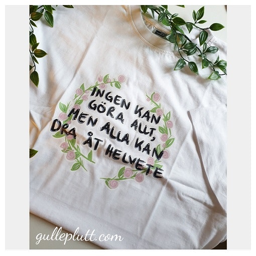 Vit T-shirt Blomkrans, med citatet "Ingen kan göra allt, men alla kan dra åt helvete"