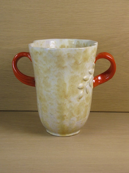 large yellowish vase with orange handles