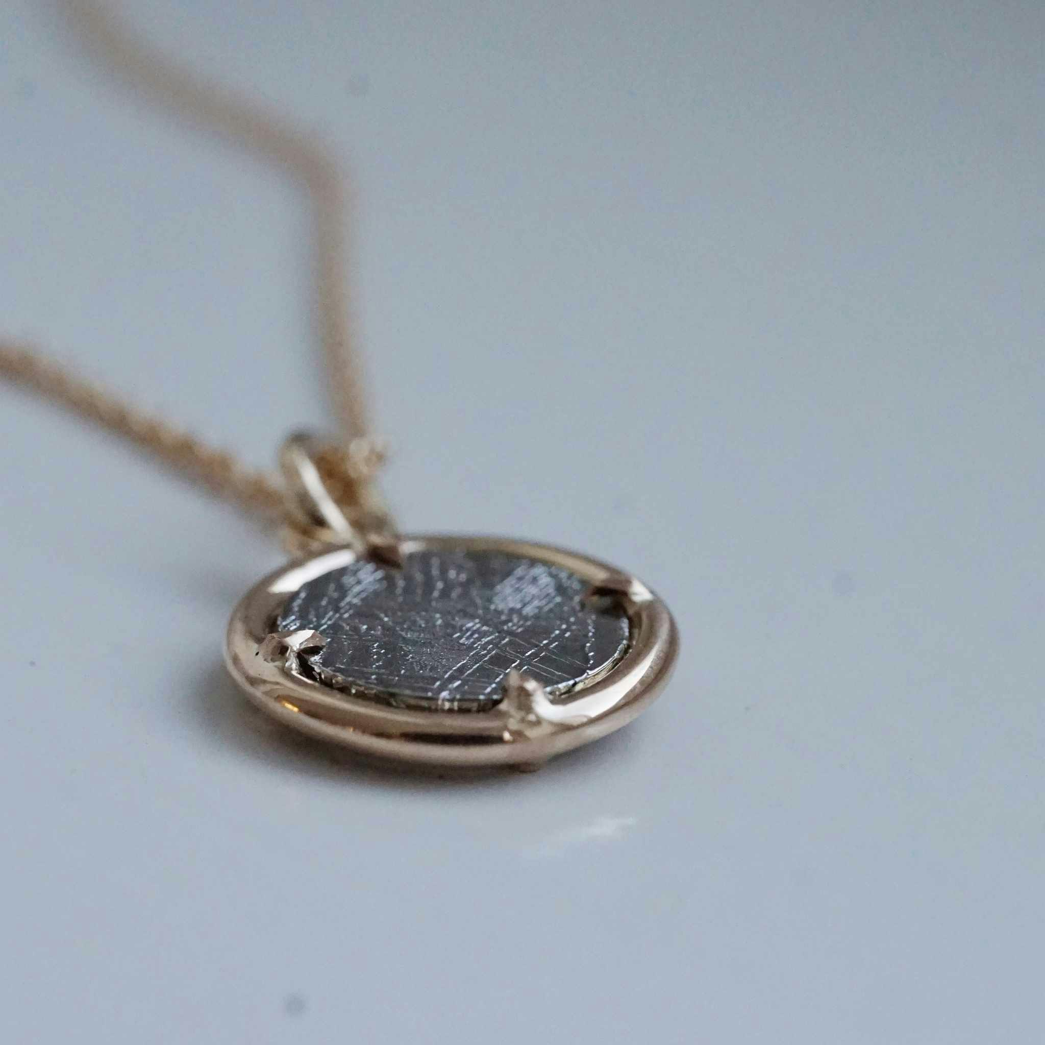 "Muonionalusta" pendant in gold with a meteorite slice