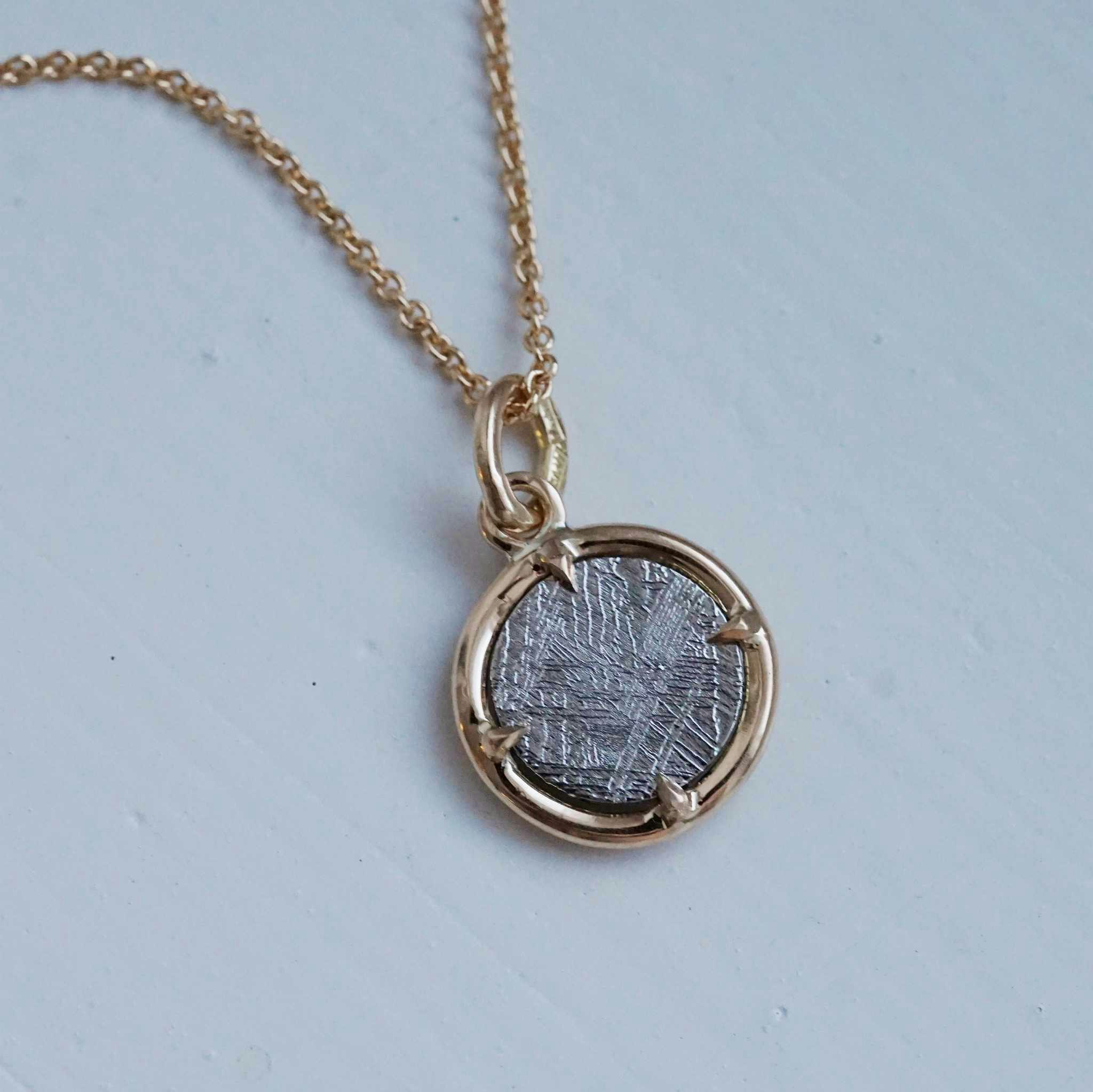 "Muonionalusta" pendant in gold with a meteorite slice