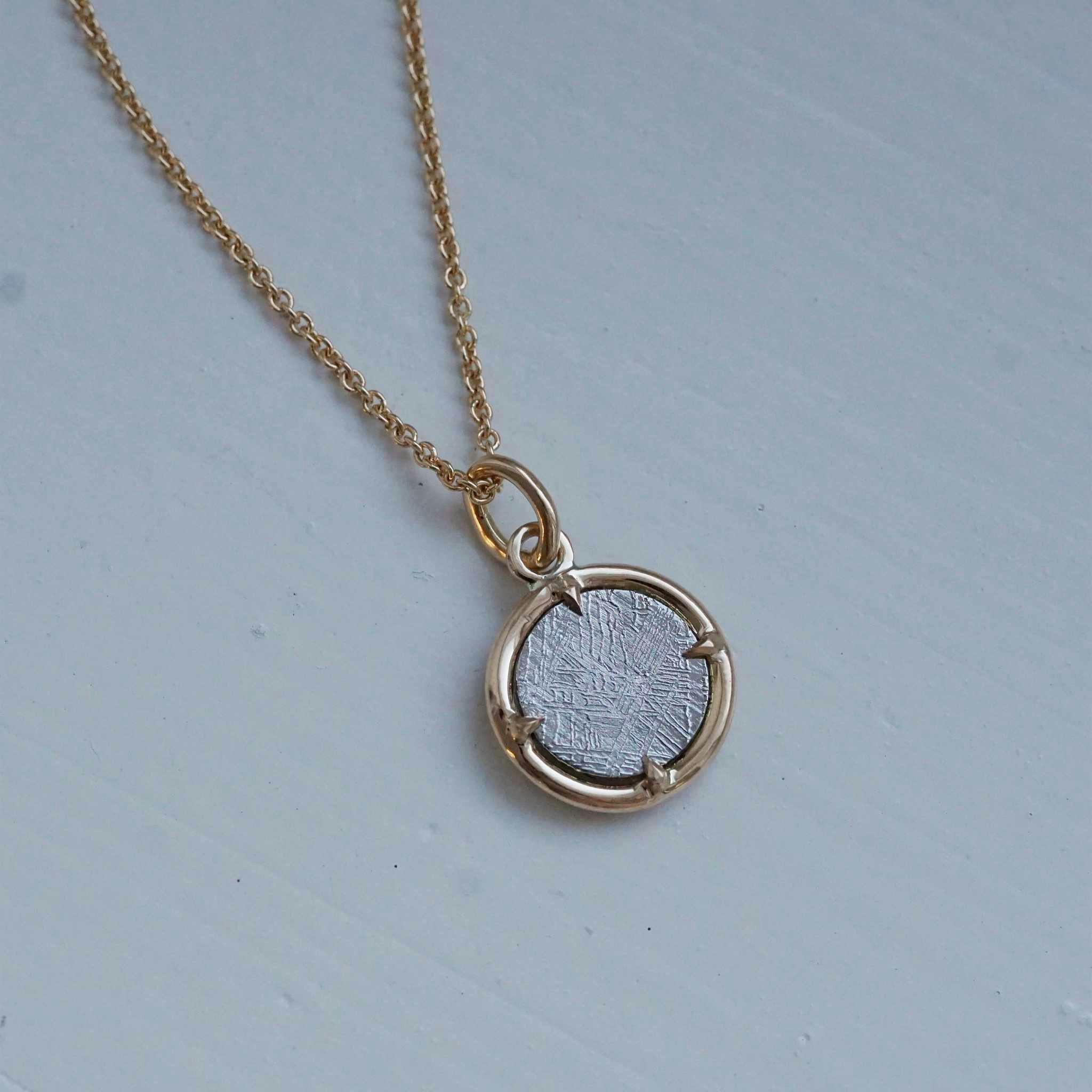 "Muonionalusta" pendant in gold with a meteorite slice